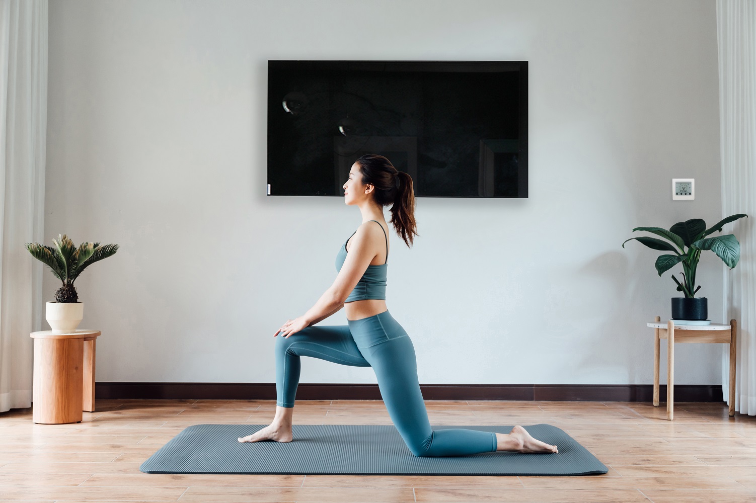 Un elegante calentador Herschel de vidrio negro calienta a una mujer que practica yoga en casa.