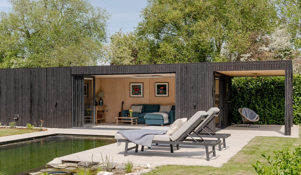 la caseta de la piscina cuenta con revestimiento de madera Yakisugi (madera carbonizada), techo de sedum y grandes puertas plegables que se abren a las vistas de la cada vez más popular piscina natural, una tendencia en auge en el paisajismo sostenible.